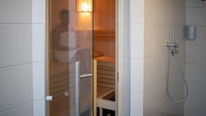 Une porte vitrée donne accès à une pièce équipée d’une douche et d’un porte-serviettes.