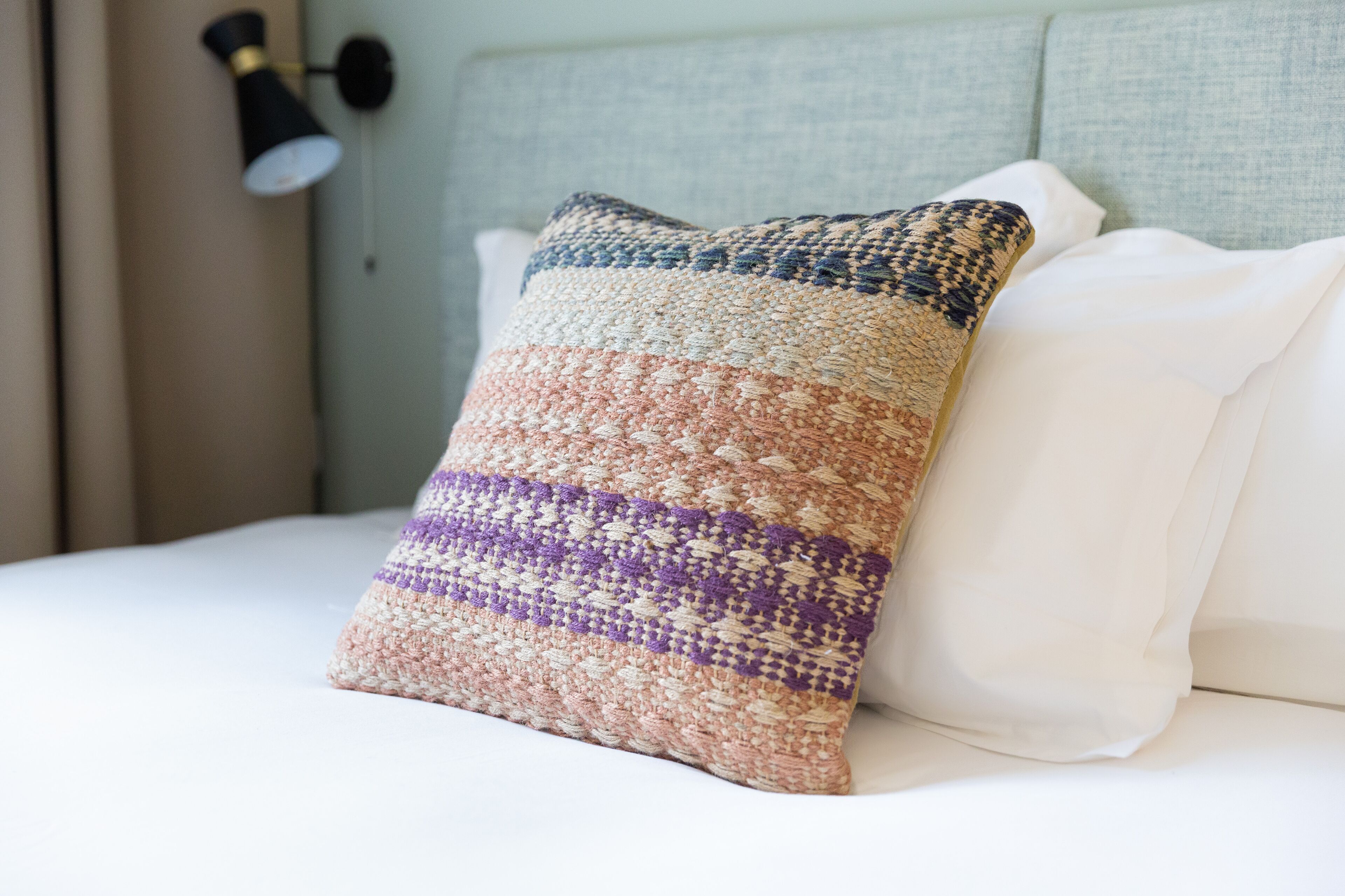 A bed with a textured pillow and a plain white pillow.