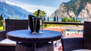 Une table en osier, avec deux verres et une bouteille, donnant sur un lac de montagne.