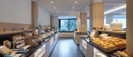 Un desayuno tipo buffet moderno con una gran variedad de alimentos y vistas al exterior.