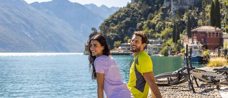 Una pareja sentada a orillas de un lago, con montañas al fondo.