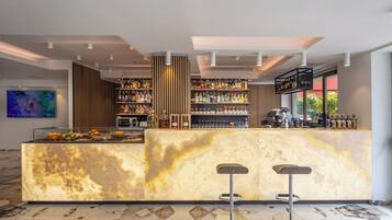 Un'area bar moderna con un bancone in marmo, due sgabelli e scaffali pieni di bottiglie e bicchieri.