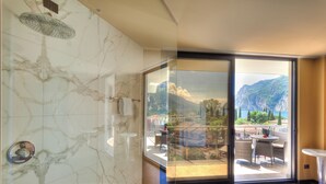Une salle de bain moderne avec douche, une porte vitrée donnant sur un balcon avec vue sur la montagne.