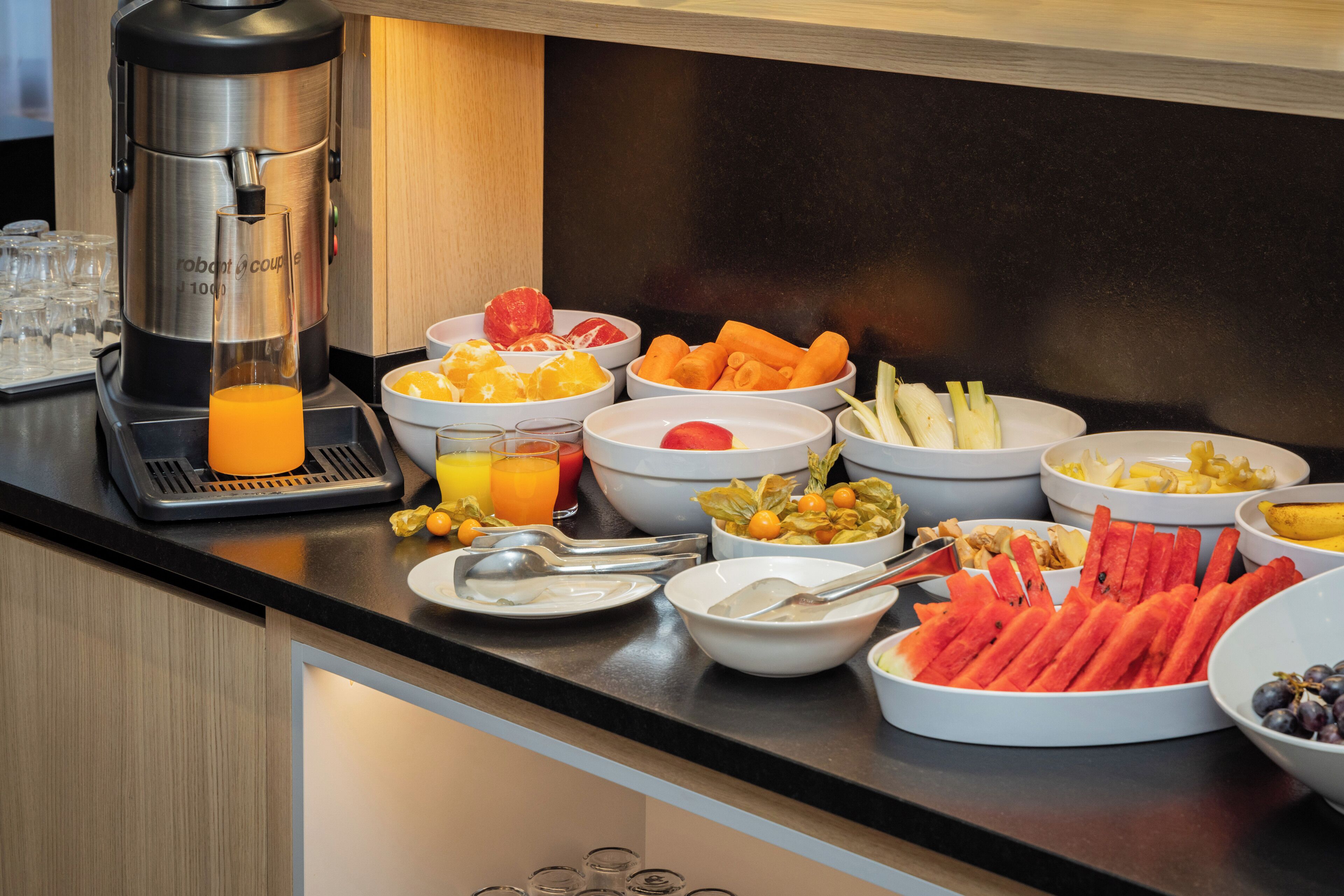 A breakfast buffet with various fruits, vegetables, and beverages.