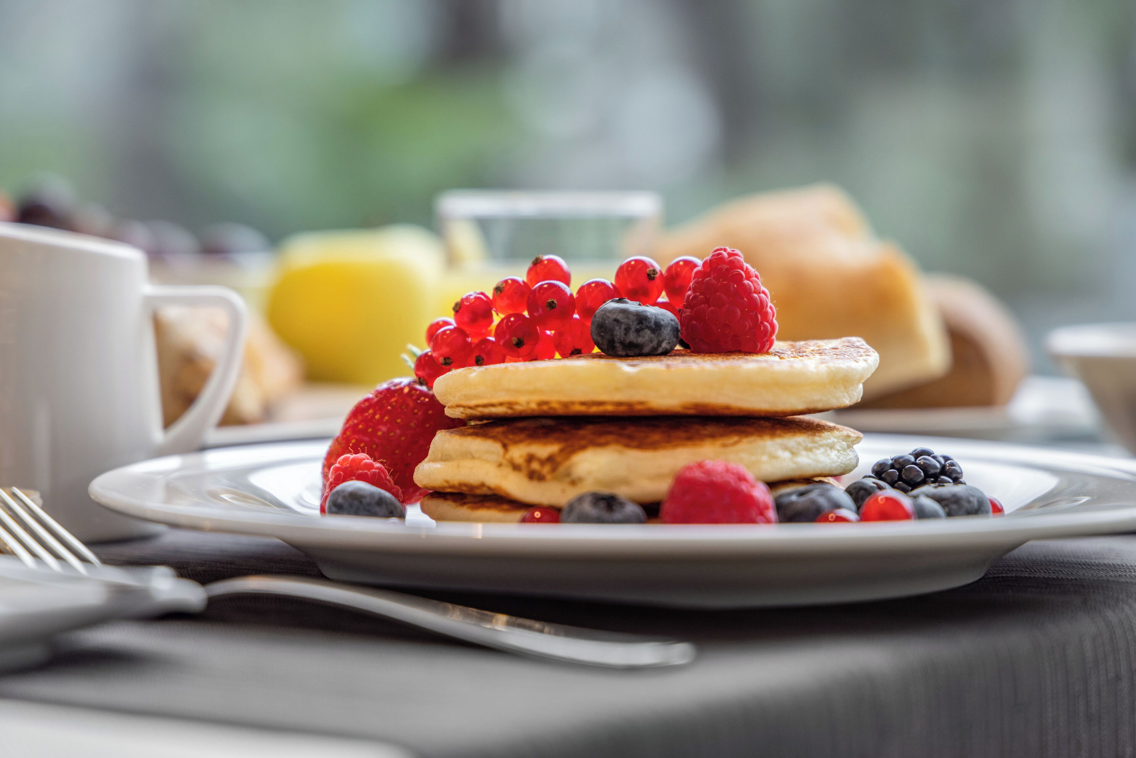 Une assiette de petit-déjeuner avec des crêpes, des fraises, des myrtilles et des framboises.
