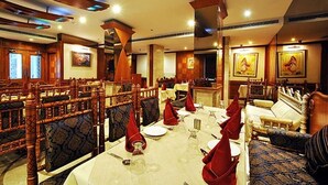 Un restaurant avec des meubles en bois, des serviettes rouges et des œuvres d’art encadrées accrochées aux murs.