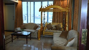 Un salon luxueux avec un lit à baldaquin doré, deux canapés et une table basse.