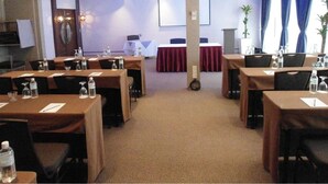 Un salón de conferencias con varias mesas, sillas y un atril.