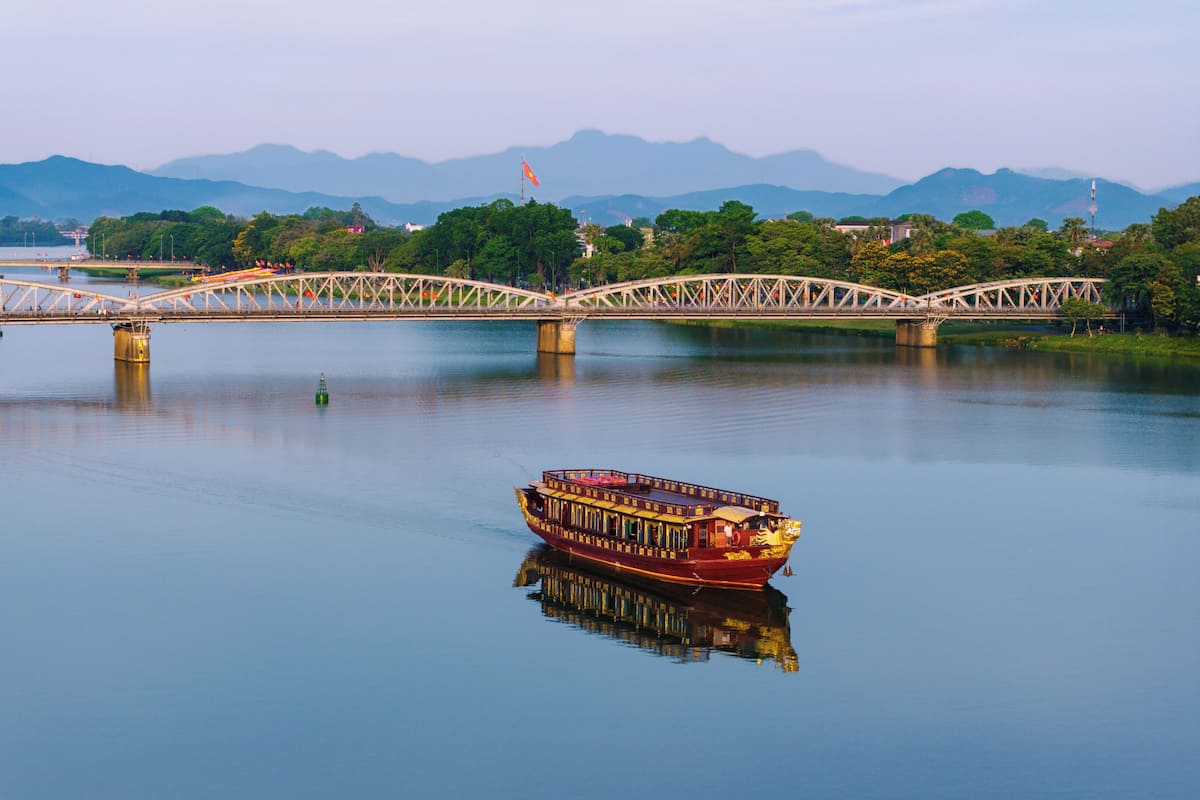 A river with a traditional boat and a bridge in the background.