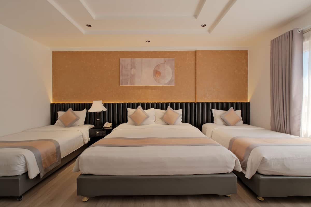 A hotel room with three beds, a large artwork on the wall, and a view of the outdoors.