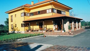 Un edificio giallo di due piani con un portico coperto e una zona salotto esterna.