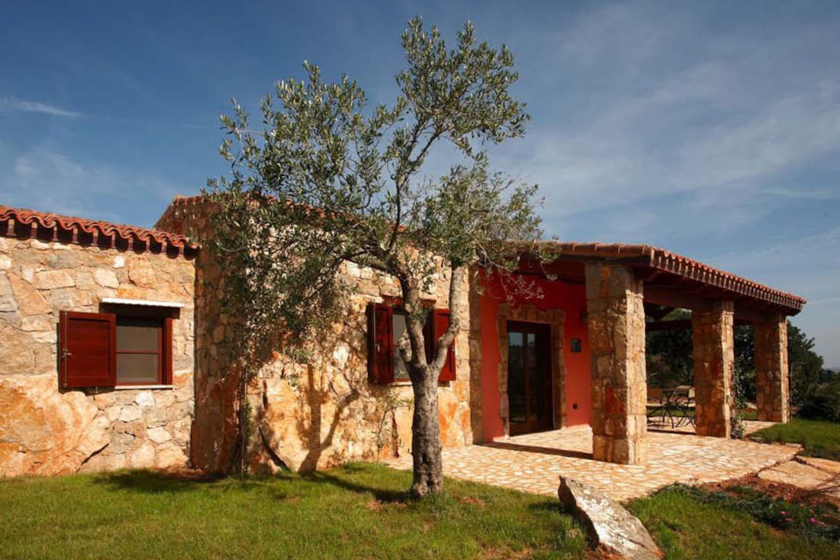 A stone building with a red door and a tiled patio.