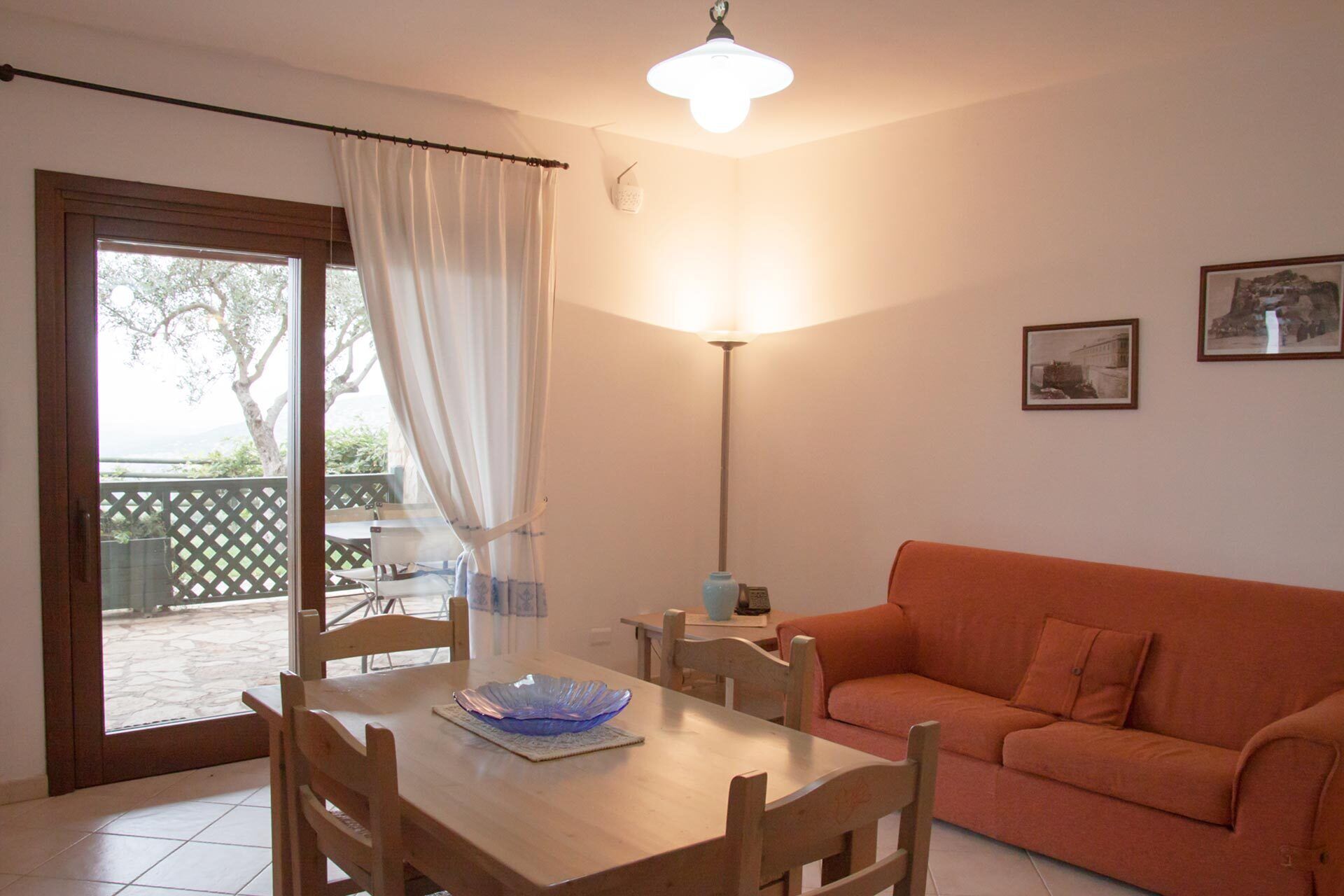 Un salón acogedor con una mesa de madera, un sofá naranja y una zona de comedor con sillas.