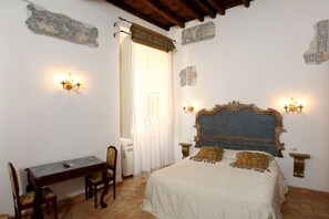 A bedroom with a bed, a desk, and chairs. There are wall sconces and a decorative headboard. - Navona Governo Vecchio (Rome)