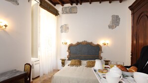 A hotel room with a bed, a dining table with breakfast items, and decorative wall pieces. - Navona Governo Vecchio (Rome)