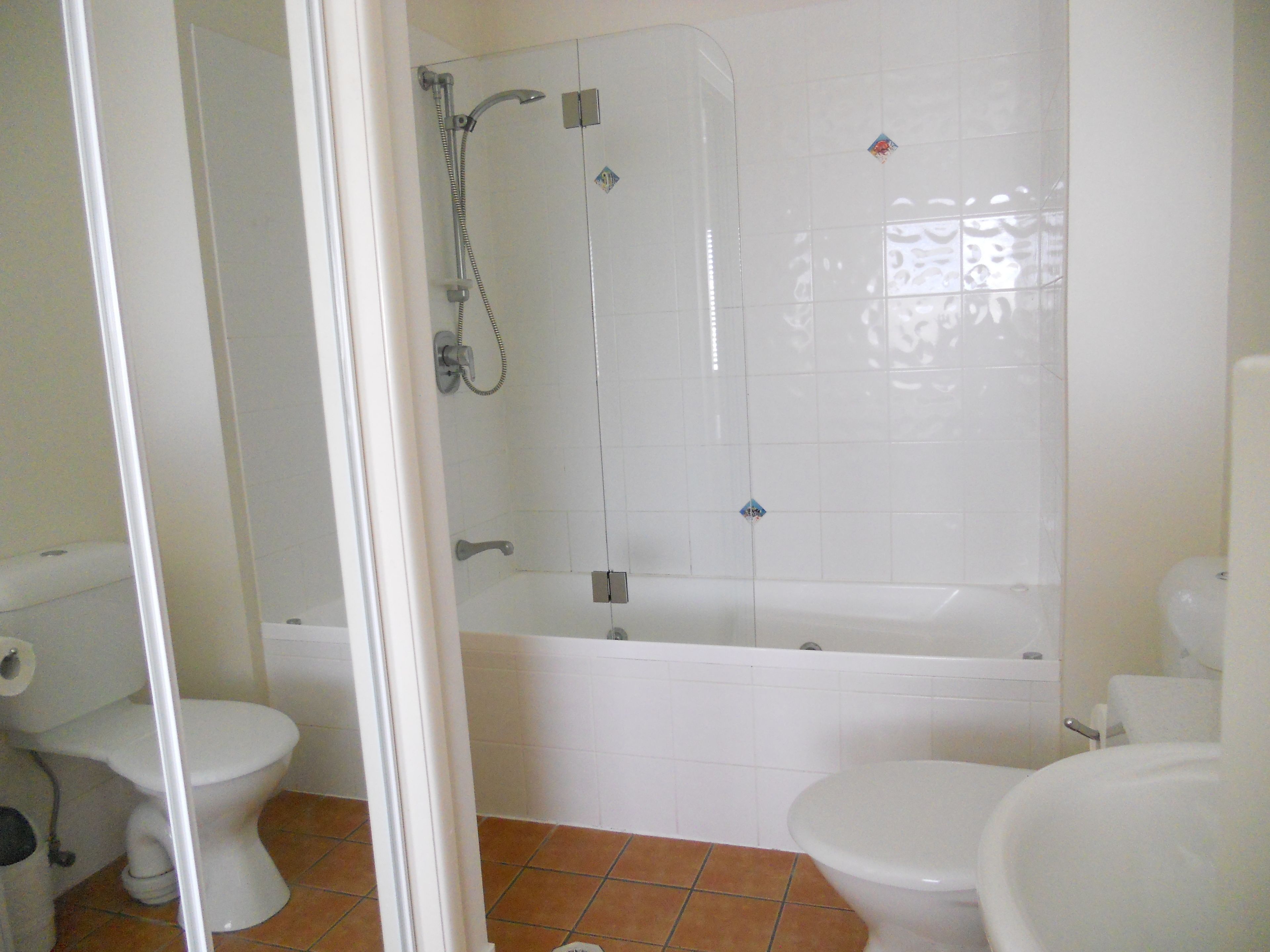 A bathroom with a shower, toilet, and bathtub.