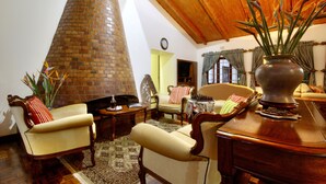 A cozy living room with a brick fireplace, comfortable seating, and a wooden ceiling.