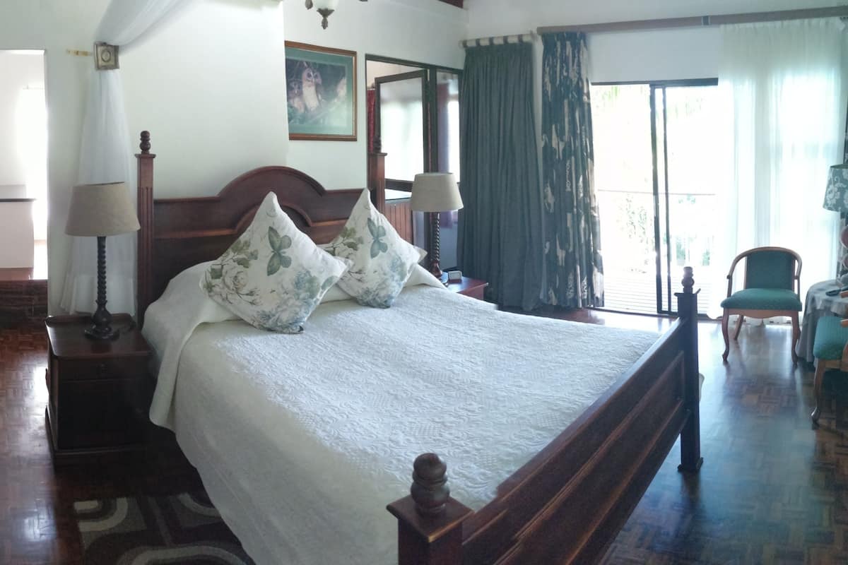 Un dormitorio ordenado con una cama de madera, una mesita de noche, una lámpara y una silla.