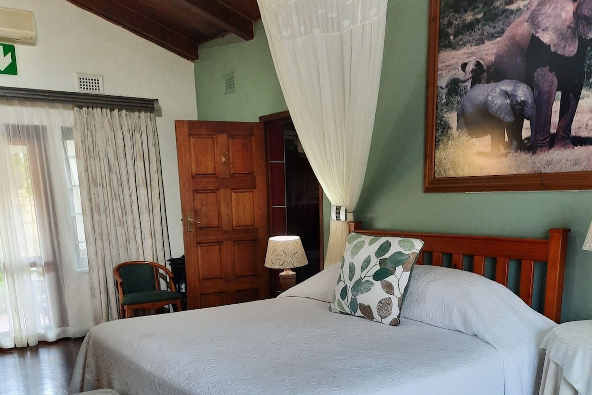 Un dormitorio con una cama grande, una mesita de noche, una silla y una puerta de madera.