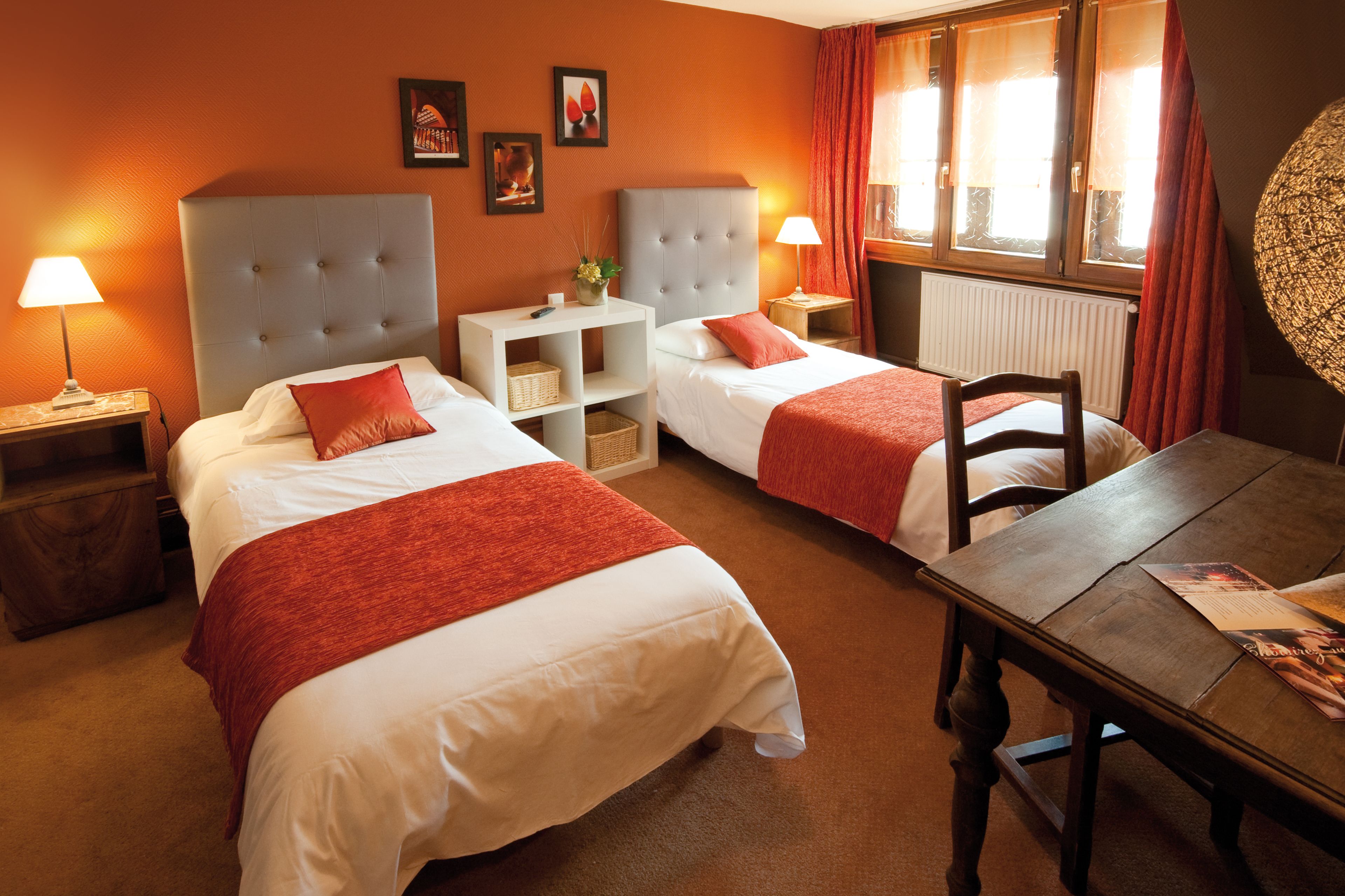 A hotel room with two beds, a dining table, and a window with curtains.