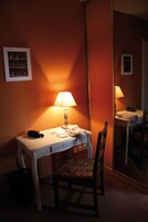 Una habitación de hotel con escritorio, silla, lámpara y espejo.