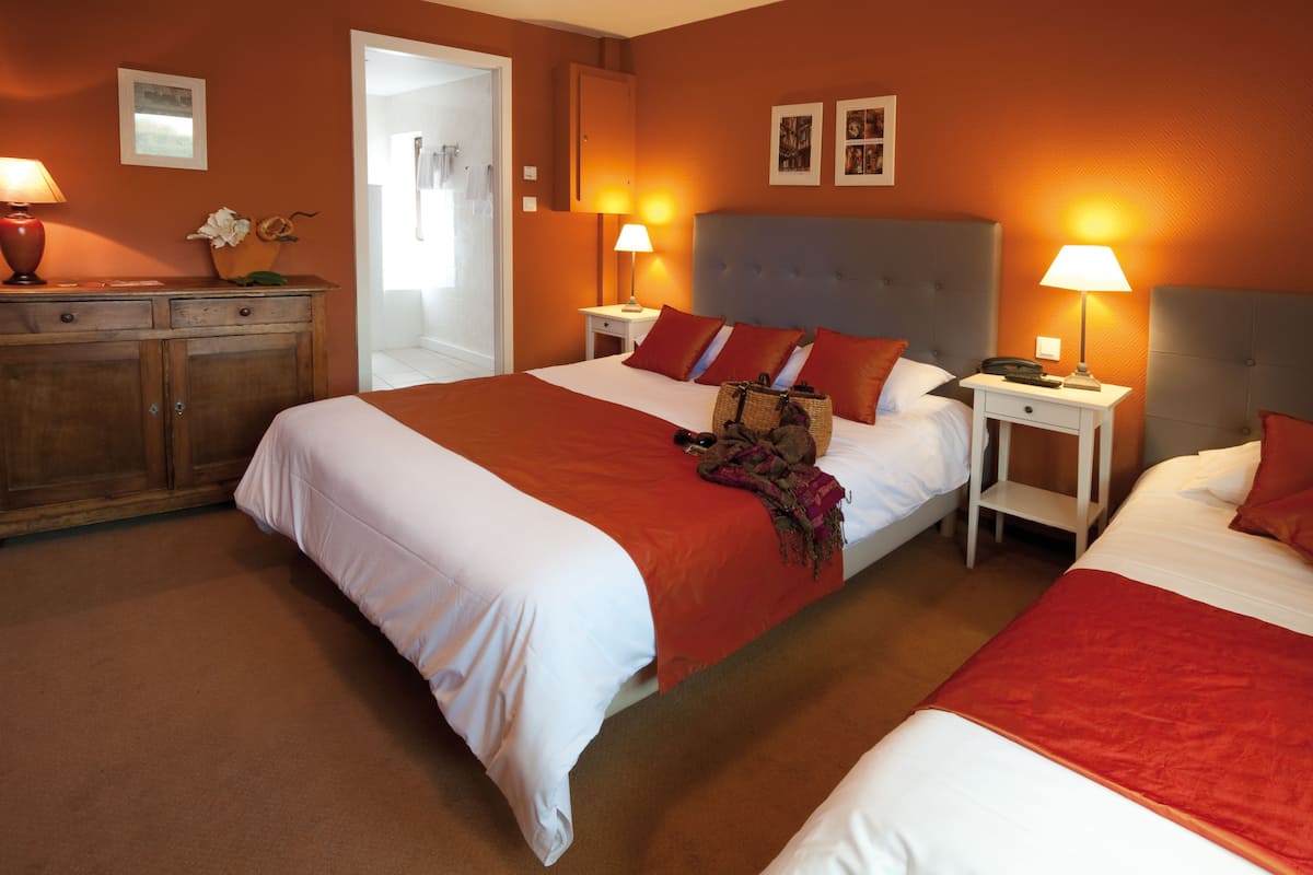 A hotel room with two beds, a wooden dresser, and two bedside tables with lamps.
