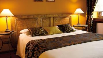 A hotel room with a large bed, two bedside tables with lamps, a headboard, and a window with curtains.