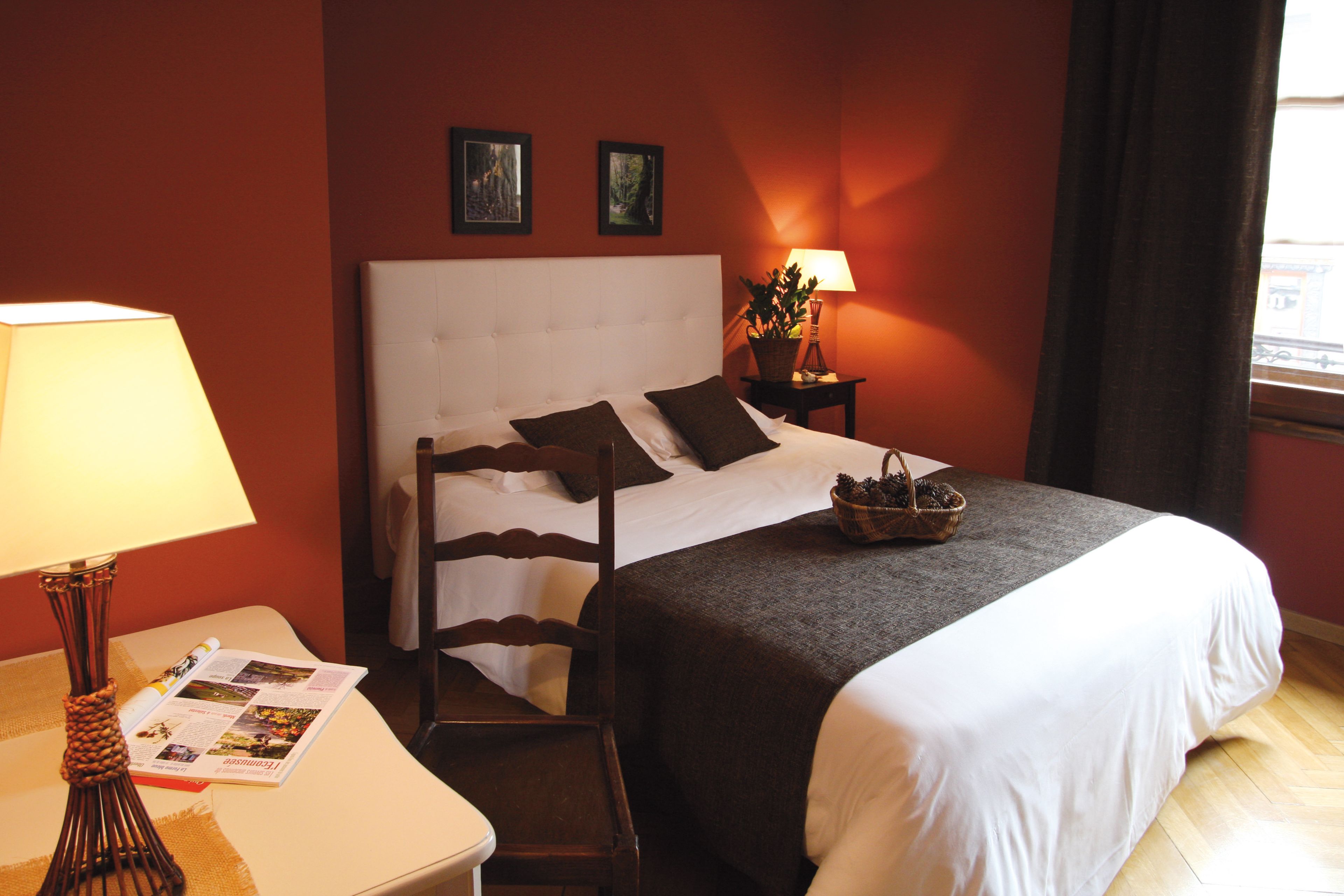Une chambre d’hôtel avec un lit, une table de chevet, une lampe et une fenêtre avec des rideaux.