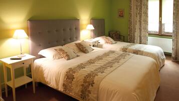 Une chambre d’hôtel avec deux lits, chacun doté d’une table de chevet et d’une lampe, une fenêtre avec des rideaux et un radiateur.