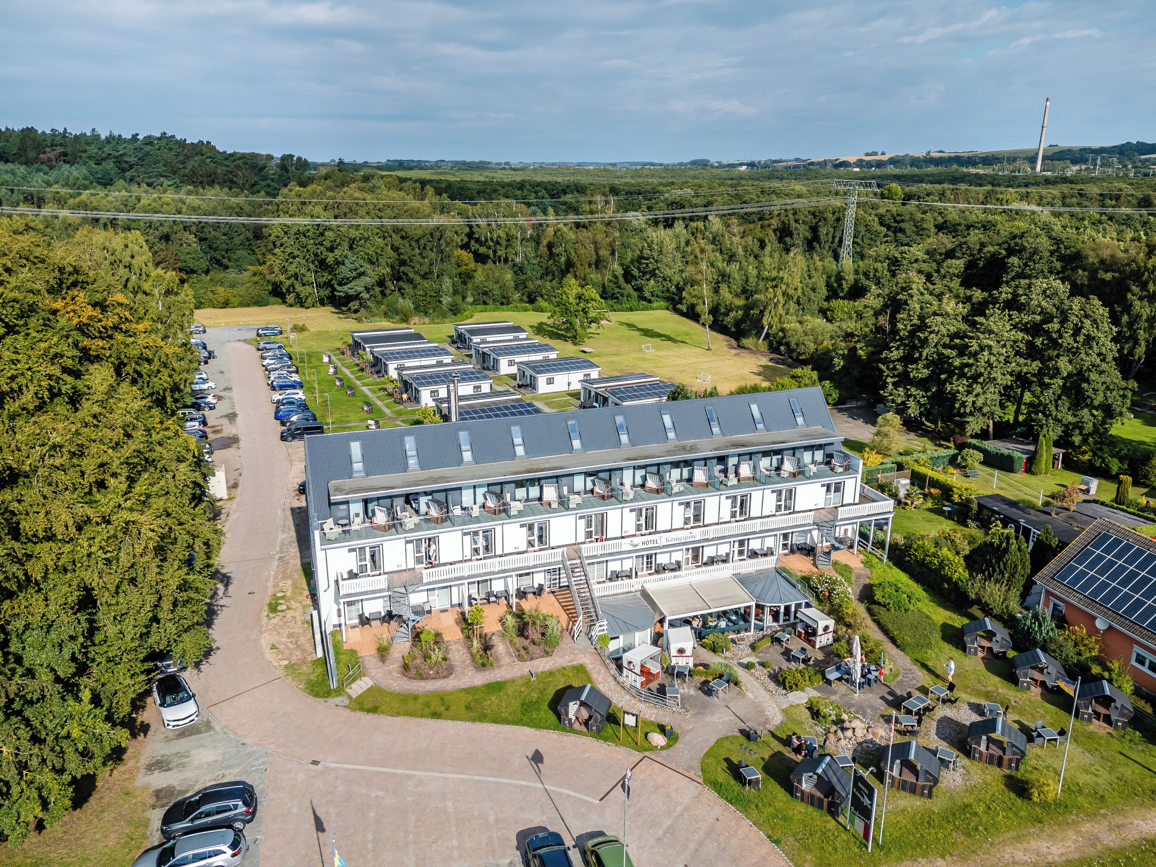 Et hotel med flere bygninger, parkeringsplads og grønne områder omkring.