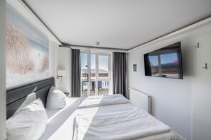 A hotel room with a bed, a television, and a view of the outdoors. - Aparthotel Koenigslinie (Sassnitz)