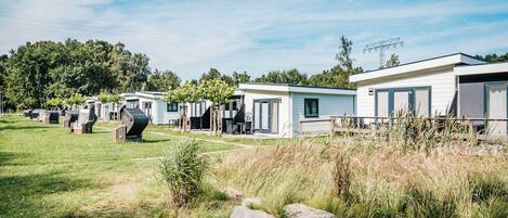 A row of mobile homes with a grassy lawn and trees in the background.