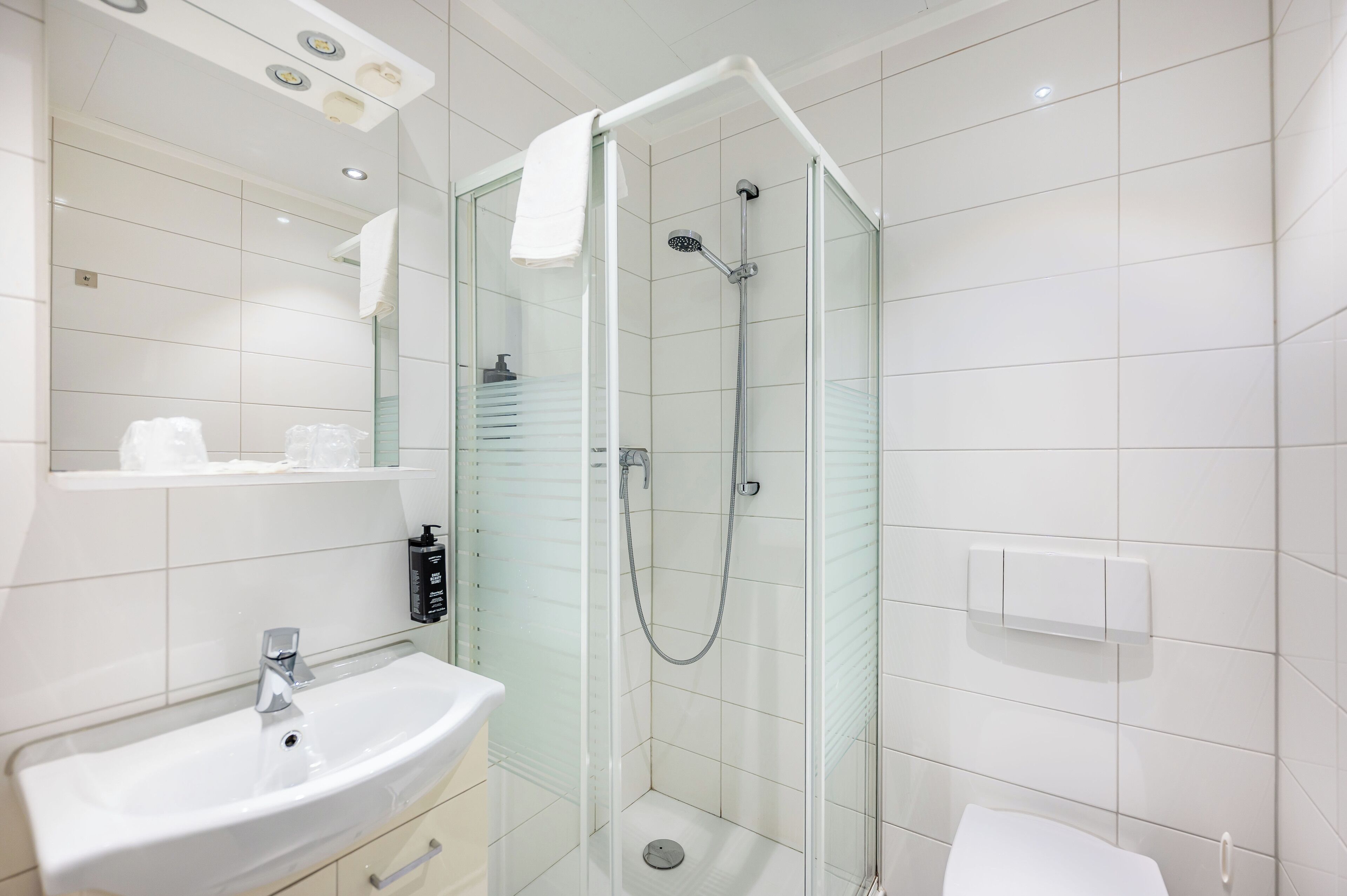 Un baño moderno con ducha de vidrio, lavamanos y retrete.