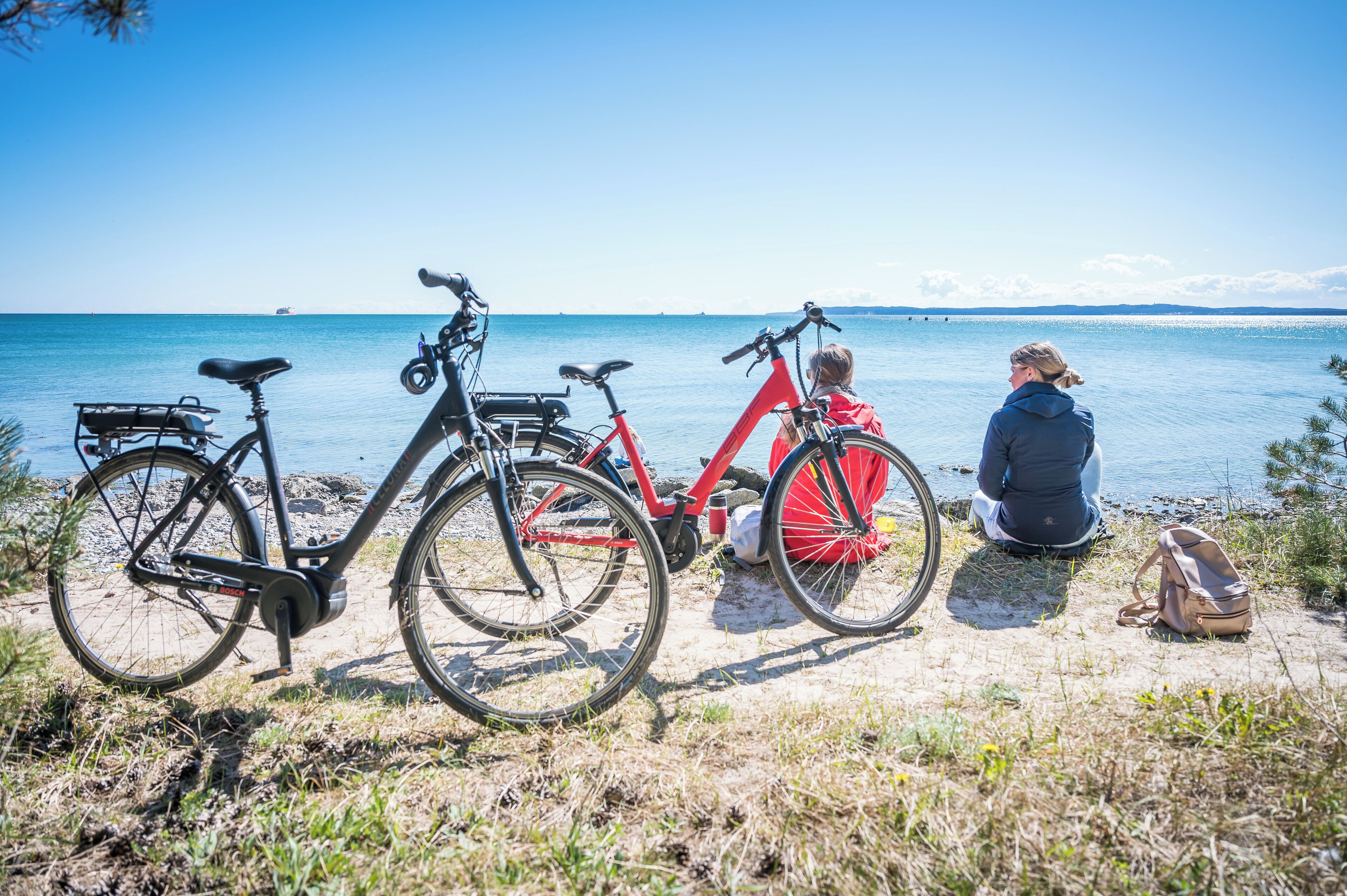 A beach with bicycles and a person sitting on the sand.