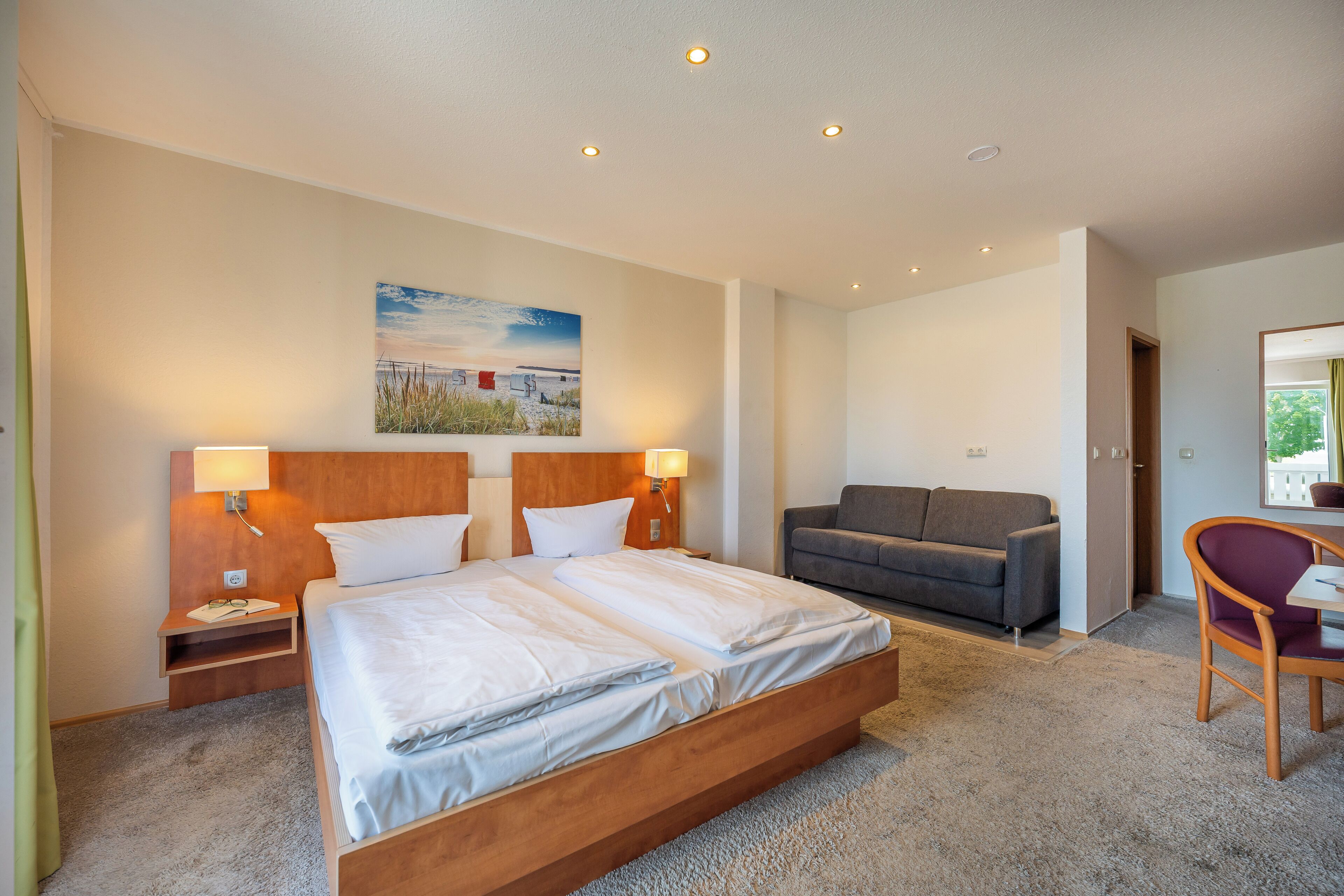 A modern hotel room with a large bed, a sofa, and a chair.