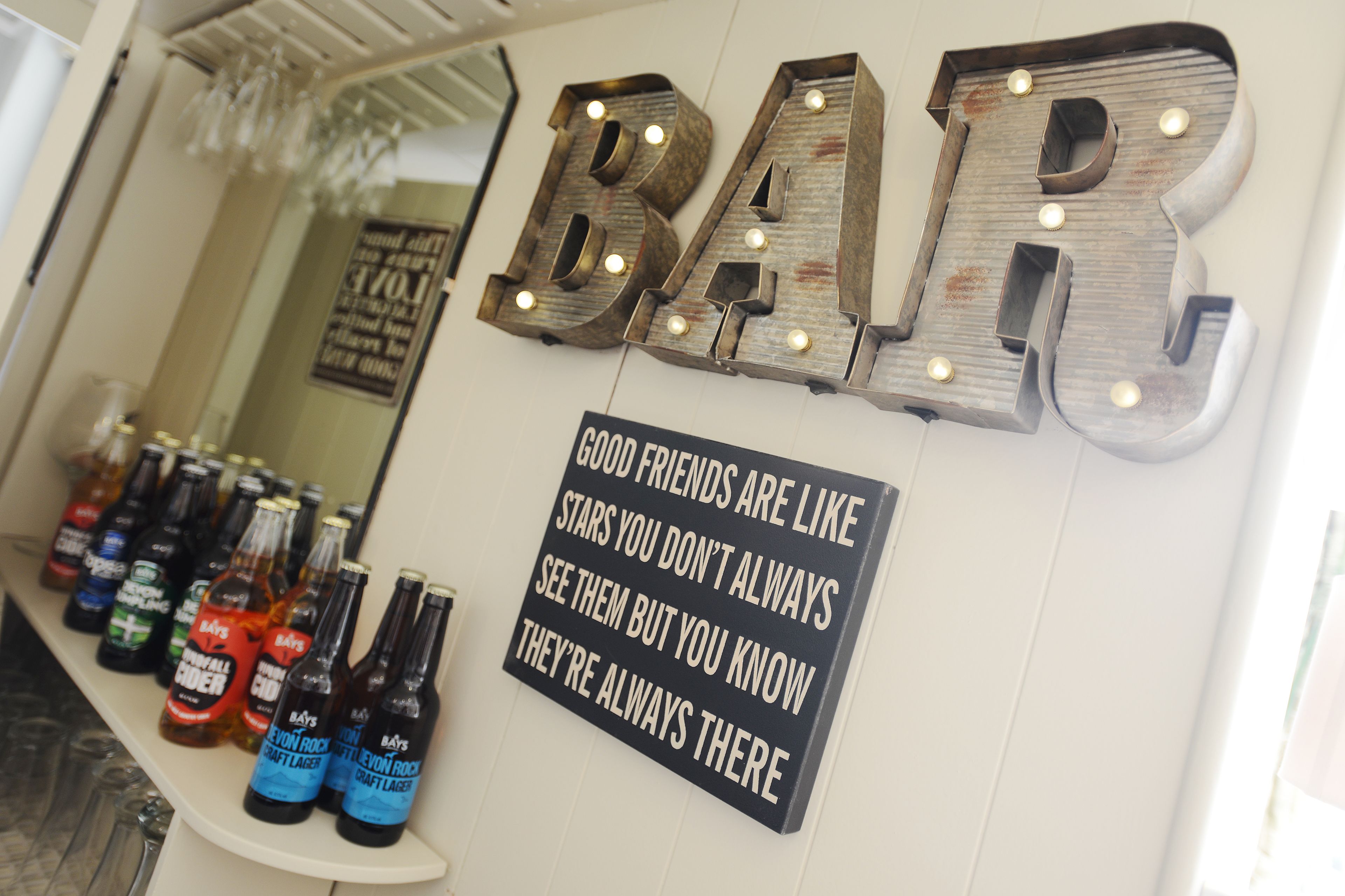 Un bar avec des lettres lumineuses qui épellent le mot « BAR » et une pancarte indiquant : « Les bons amis sont comme les étoiles : on ne les voit pas toujours, mais on sait qu’ils sont toujours là. »