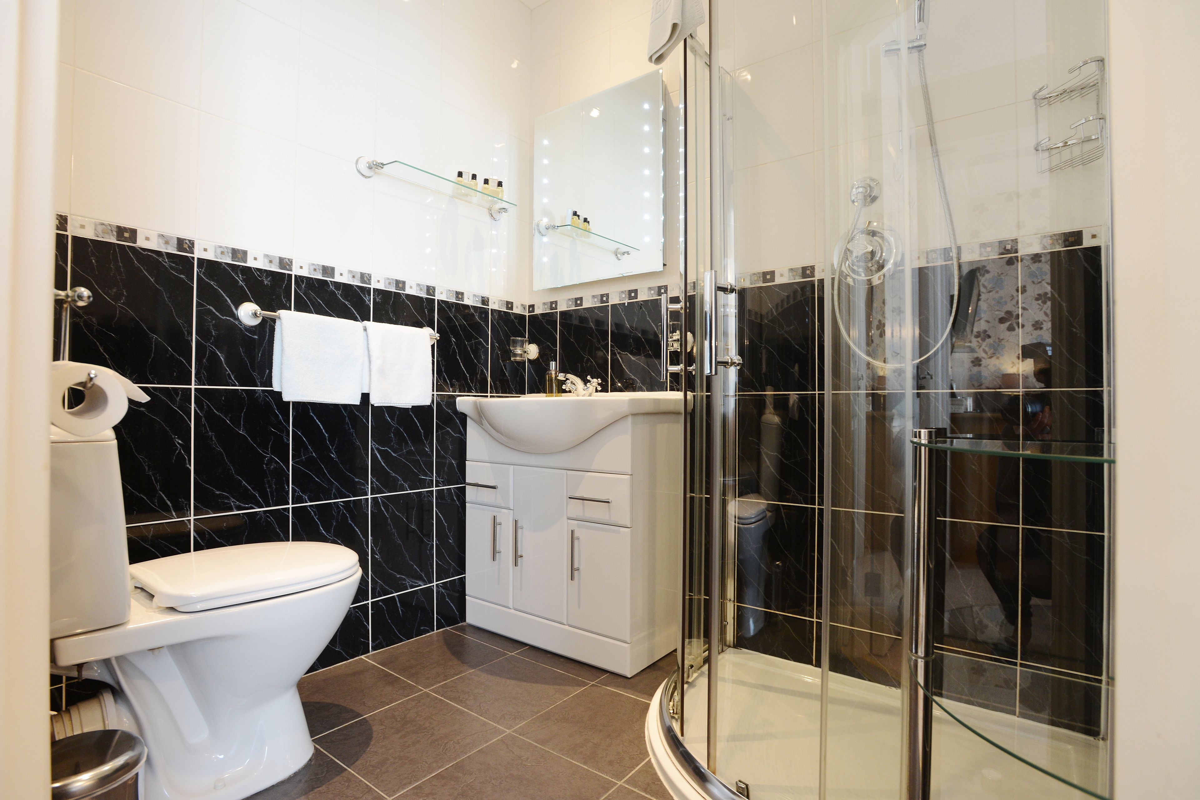 Une salle de bain moderne équipée de toilettes, d’un meuble-lavabo et d’une douche à parois de verre.