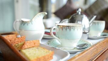 A tray with a teapot, cups, saucers, and slices of cake on a wooden table.