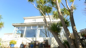 Un bâtiment blanc avec de grandes fenêtres et un mur de pierre à l’avant.