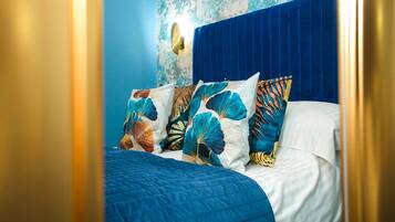 Un lit avec une tête de lit bleue et des oreillers à motifs floraux.