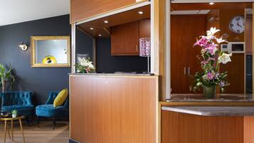 A reception area with a wooden desk, a clock, and a mirror.
