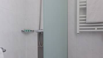 Un baño con ducha, inodoro y perchero para toallas.