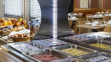Un buffet proposant une variété de plats, notamment des fruits, des œufs et de la viande.