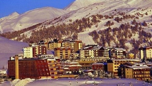 Un pueblo cubierto de nieve con edificios y una montaña al fondo.