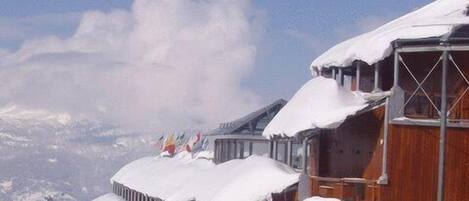 Un edificio de madera con tejados nevados y cielo despejado.