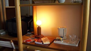 Un escritorio con lámpara, libros y monitor de computadora.