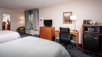 Habitación de hotel con dos camas, un escritorio con computadora, televisor, microondas y refrigerador.