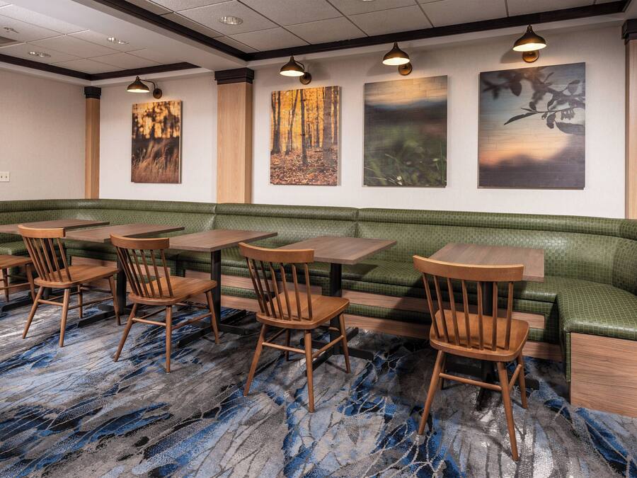A restaurant with a green cushioned bench, wooden tables, and chairs.