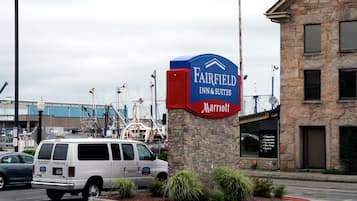 Señal de Fairfield Inn & Suites con el logotipo de Marriott, una furgoneta blanca y un edificio de fachada de piedra.