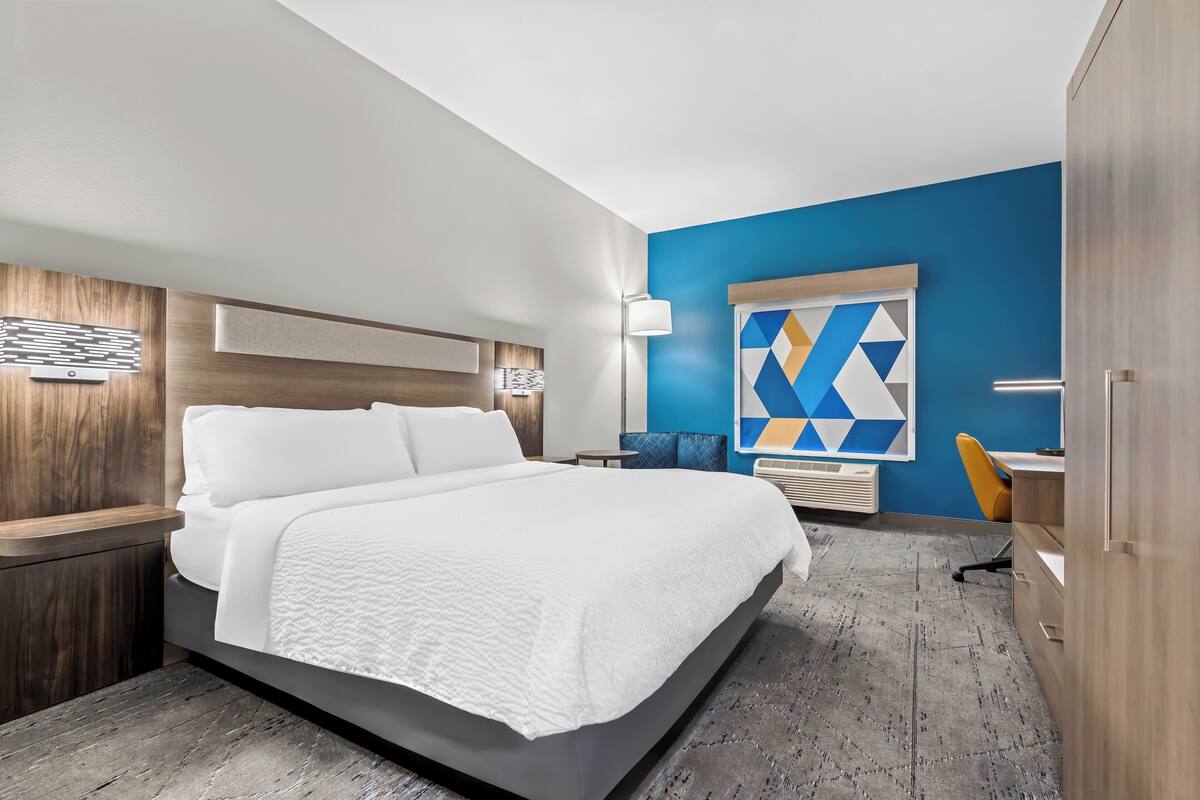 A modern hotel room with a large bed, a desk, and a chair.